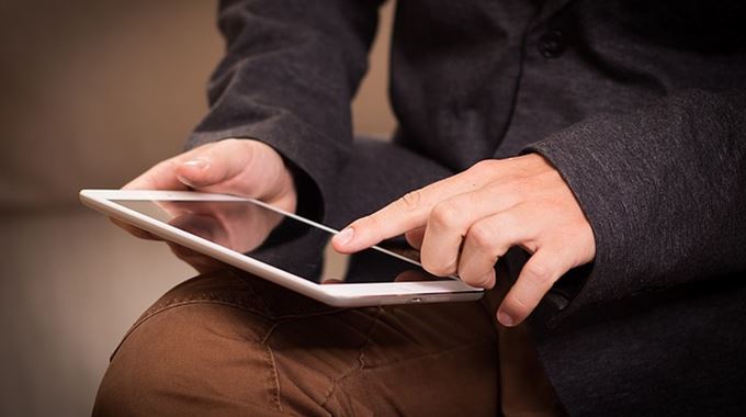 Homme lisant sur tablette électronique